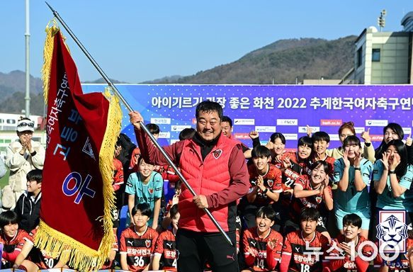 포항여전고 허문곤 감독이 우승기를 들어보이며 활짝 웃고 있다.